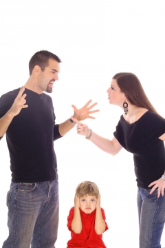 Eine Mann und eine Frau streiten, das Kind in der Mitte hält sich die Ohren zu